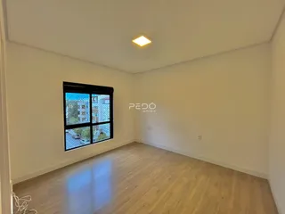 Sala de estar com piso de madeira clara e janela grande.