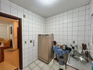 Interior da cozinha com paredes brancas e piso de cerâmica.