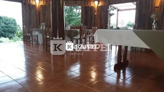 Foto do interior de um ambiente com piso de ladrilho polido e pilares de madeira.
