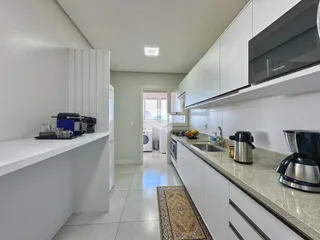 Cozinha moderna com armários brancos e bancadas claras.