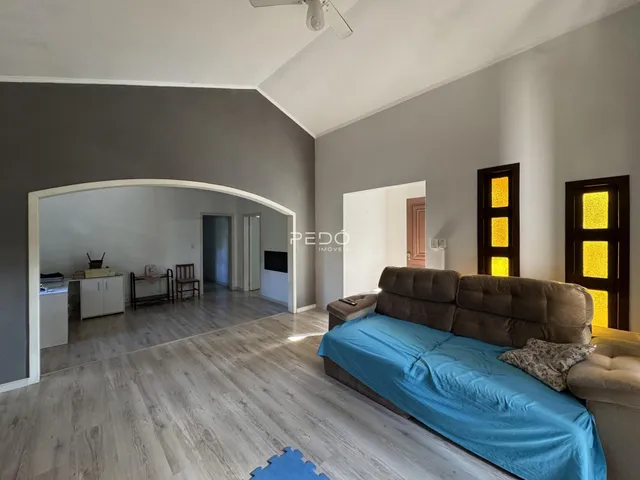 Sala de estar com piso de madeira e abertura para outra sala.