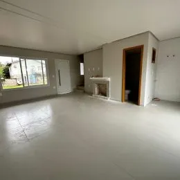 Ambiente interno amplo e vazio de uma residência com piso claro.