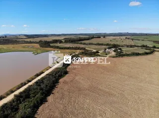Vista aérea de uma paisagem rural com um rio e campos abertos.