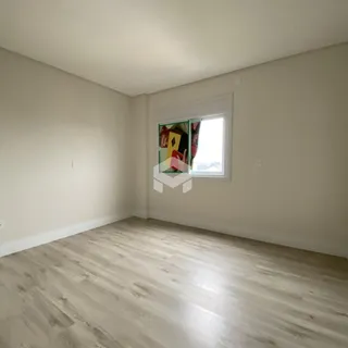 Ambiente interno de uma sala com piso de madeira clara e parede branca.