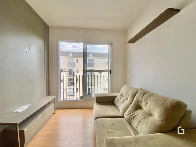 Sala de estar com piso de madeira e vista para o exterior.