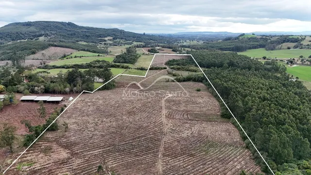 Vista aérea de um terreno rural com áreas de plantio e vegetação densa.