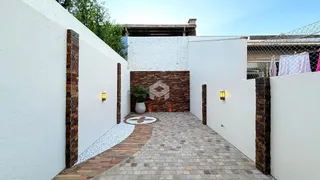 Pátio externo com paredes brancas e piso de tijolos no Lajeado.