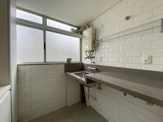 Cozinha com revestimento de azulejos brancos e janela grande.