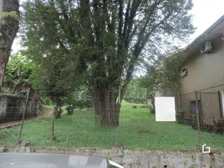 Vista externa de uma propriedade com vegetação e cerca no jardim.