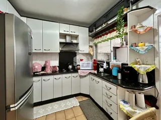 Cozinha com armários brancos e bancadas escuras.