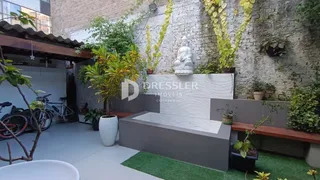 Área externa com parede de tijolo e vegetação exuberante.