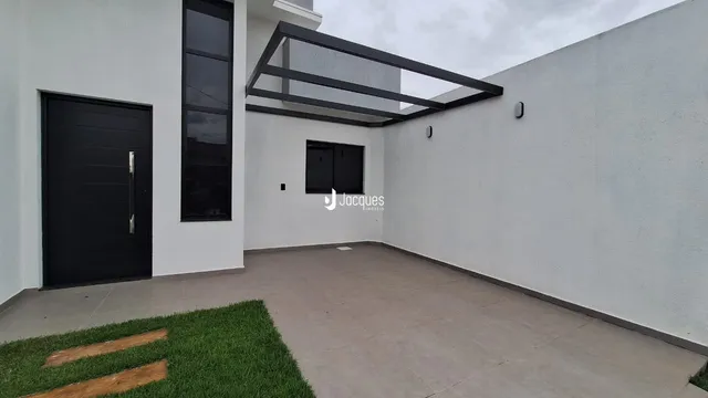 Fachada moderna de uma residência branca com porta escura e estrutura de telhado exposta.