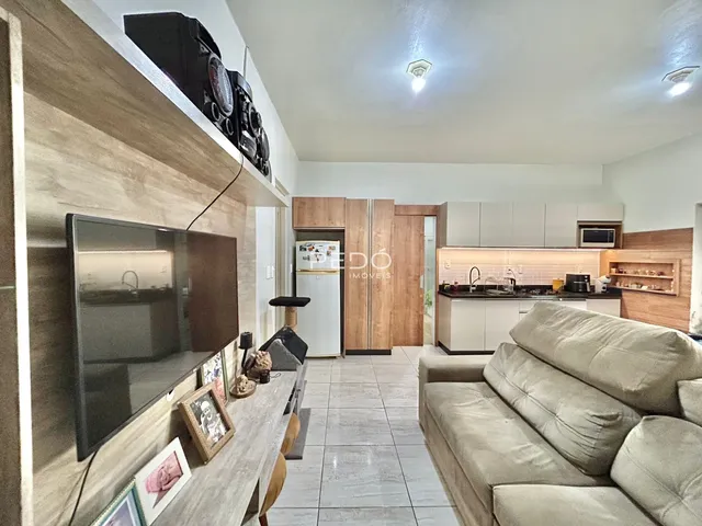 Sala de estar com decoração moderna e cozinha integrada em apartamento.