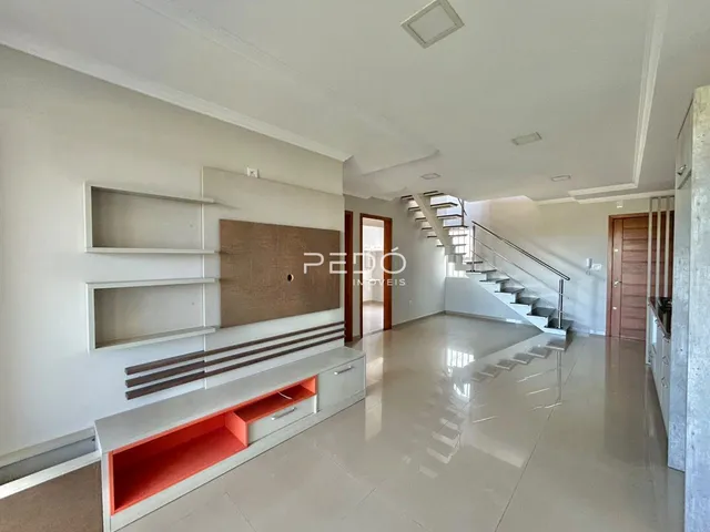 Uma sala de estar ampla com piso polido e estantes embutidas nas paredes.