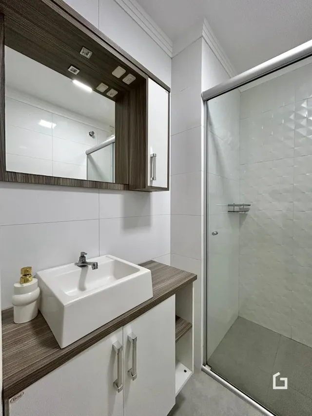 Foto de um banheiro moderno com box de vidro e bancada de madeira.
