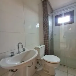 Foto de um banheiro com pia e vaso sanitário de azulejos brancos.