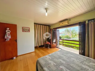 Quarto com piso de madeira e vista para o exterior.