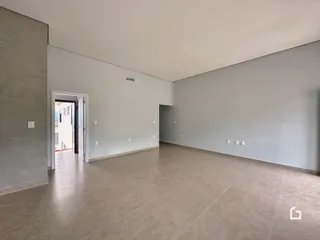 Uma sala ampla com paredes cinzas e piso de cerâmica.