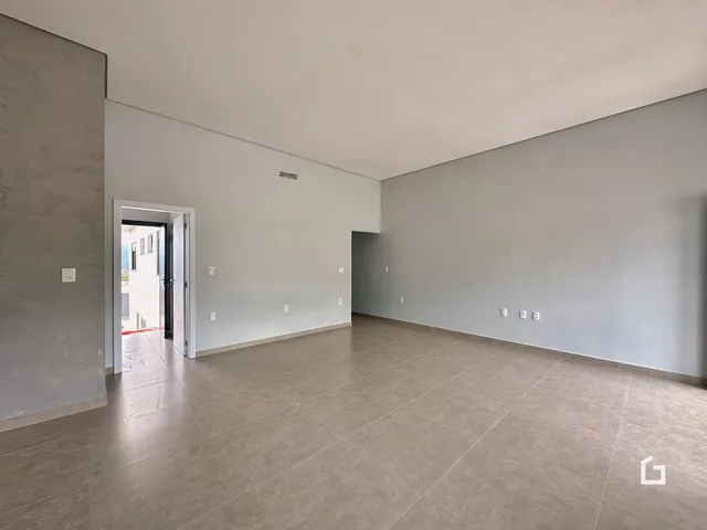 Uma sala ampla com paredes cinzas e piso de cerâmica.