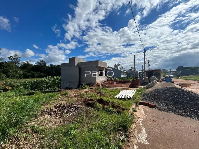 Vista externa de uma área de construção com vegetação e terra.