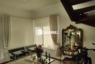 Sala de estar com cortinas brancas e móveis escuros.