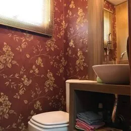 Foto de uma parede com papel de parede floral e um vaso sanitário em um ambiente.