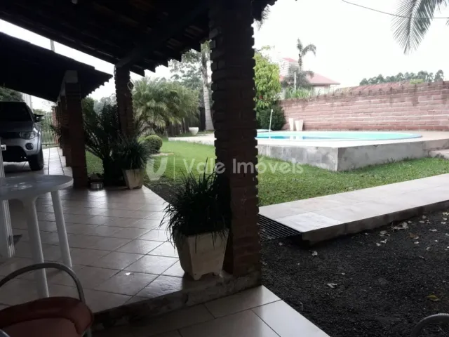 Vista externa de uma área com piso de concreto e vegetação.