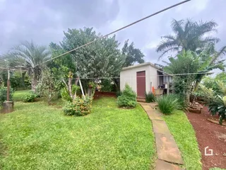 Vista externa de uma residência com jardim e gramado.