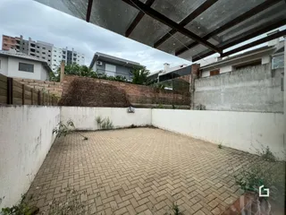 Área externa pavimentada com tijolos no quintal.