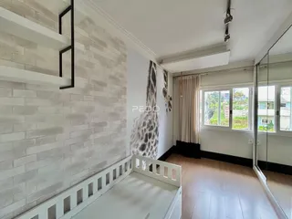 O interior de um quarto apresenta uma parede de tijolos e uma cama de estrutura branca.