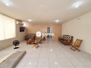 Sala de estar com sofá e cadeiras em um ambiente claro com piso de cerâmica.