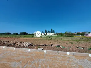 Vista de um terreno aberto com campo seco sob um céu azul.