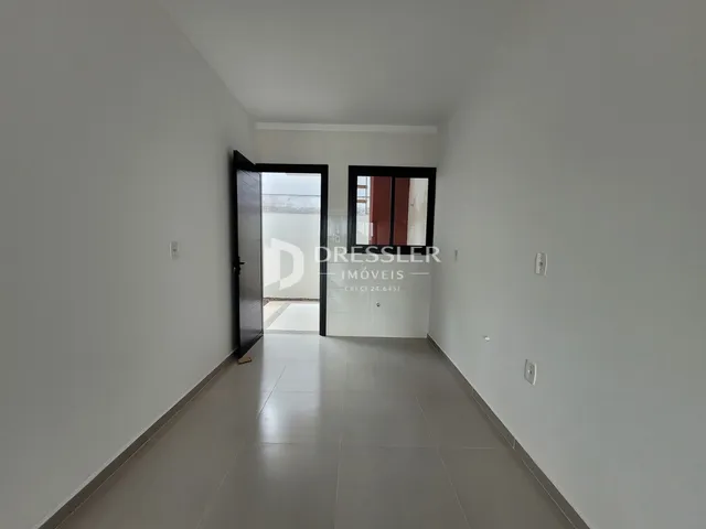 Corredor interno de uma residência com paredes brancas e piso claro.