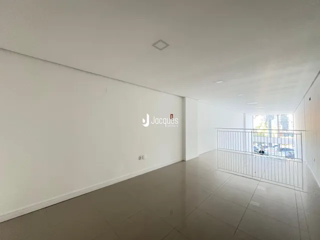 Interior de um corredor longo com paredes brancas e piso claro.