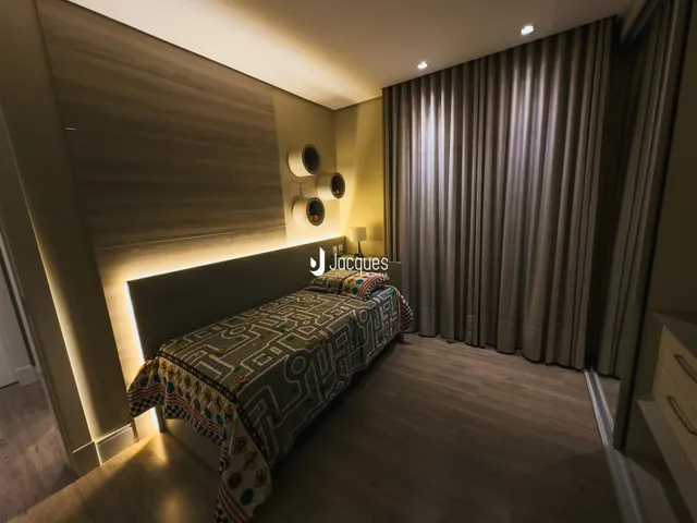 Quarto com cama e cortinas escuras em um apartamento.