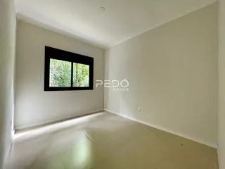 Vista interna de uma sala com uma grande janela de madeira escura.