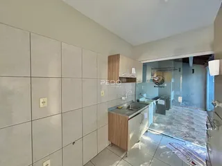Vista da cozinha com armários de madeira e revestimento cinza na propriedade.