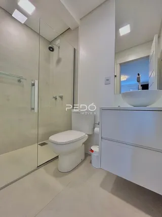 Foto do interior de um banheiro moderno com box de vidro.