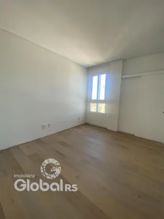 Interior de uma sala com piso de madeira clara e paredes brancas.