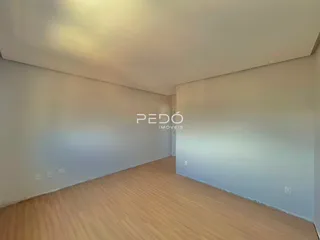 Ambiente interno de uma sala com piso de madeira clara e paredes brancas.