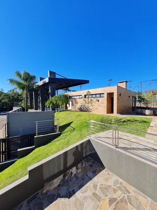 Vista externa de uma propriedade com jardim e muro de contenção.