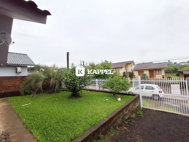 Fachada de uma residência com jardim e cerca branca em Lajeado, Brasil.