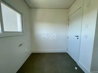 Interior de uma sala de estar com paredes brancas e piso cinza.