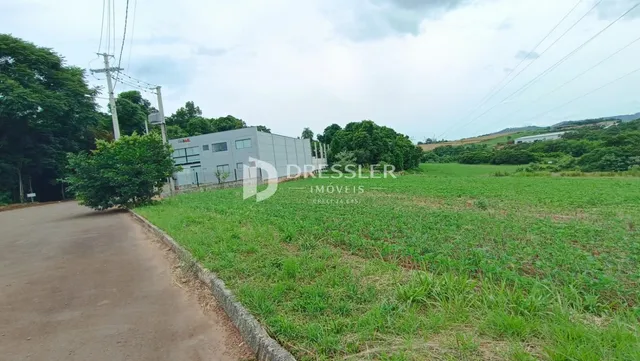 Vista externa de um imóvel com um terreno gramado e vegetação ao redor.