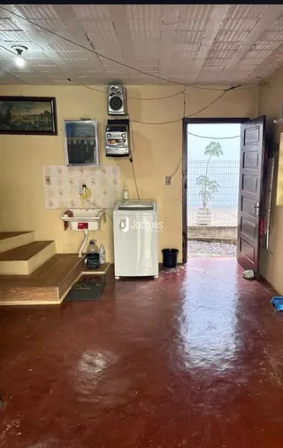 Imagem de uma sala com piso de terra avermelhada e teto de gesso.