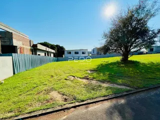 Gramado com cerca e árvores em uma propriedade residencial.