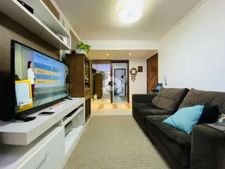 Sala de estar com sofá e televisão em um apartamento no Brasil.