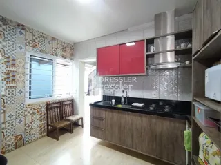 Interior de uma cozinha com armários vermelhos e piso de madeira clara.