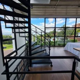 Foto de uma escadaria com corrimão preto e piso de madeira em um imóvel.