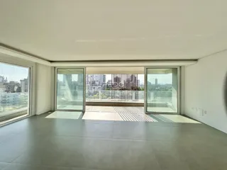 Sala de estar com grandes janelas que oferecem vista para a paisagem urbana.